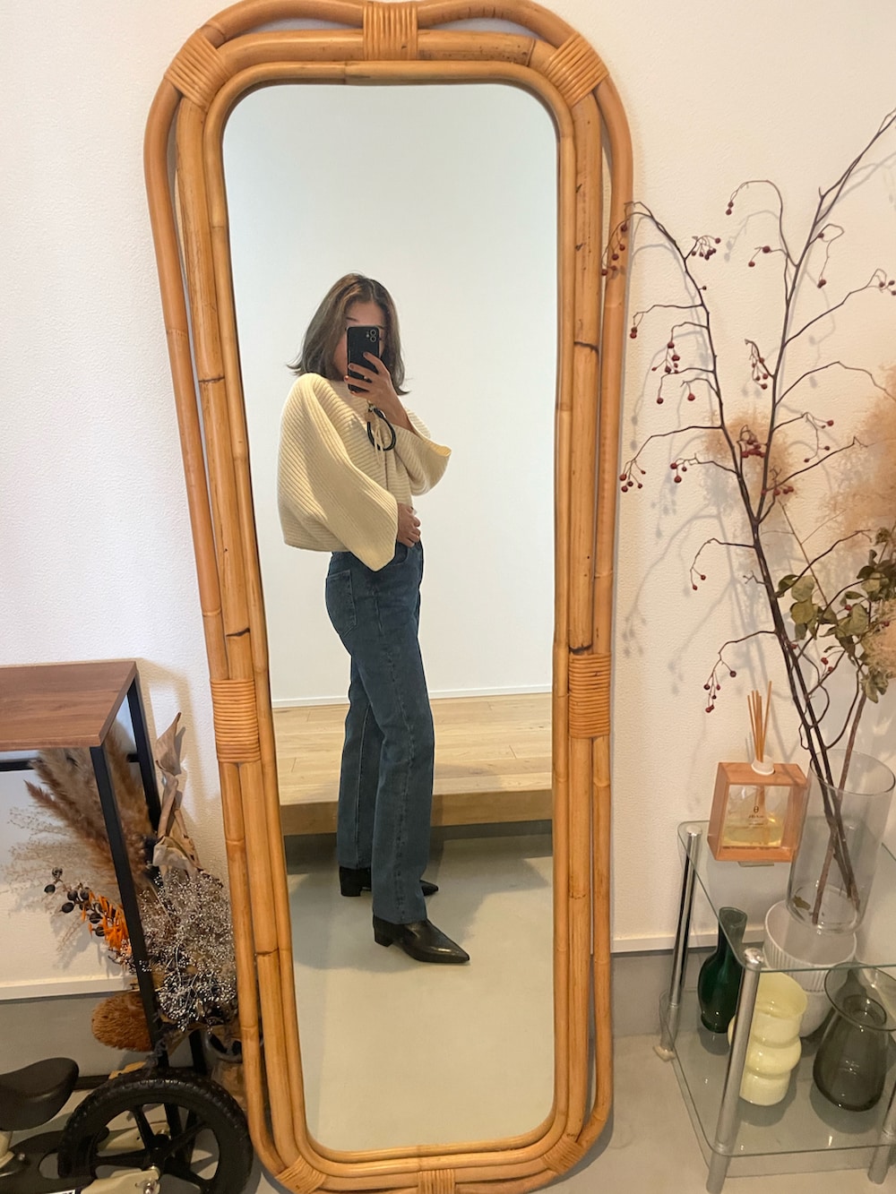 ブルー系のデニムパンツ、ブラック系のブーツ、ホワイト系のニット/セーターを着用したレディースの秋コーディネートの2枚目の写真