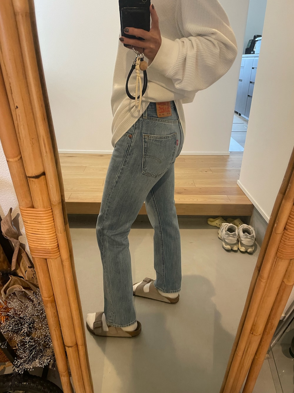 グレー系のデニムパンツ、ベージュ系のサンダルを着用したレディースの秋コーディネートの2枚目の写真