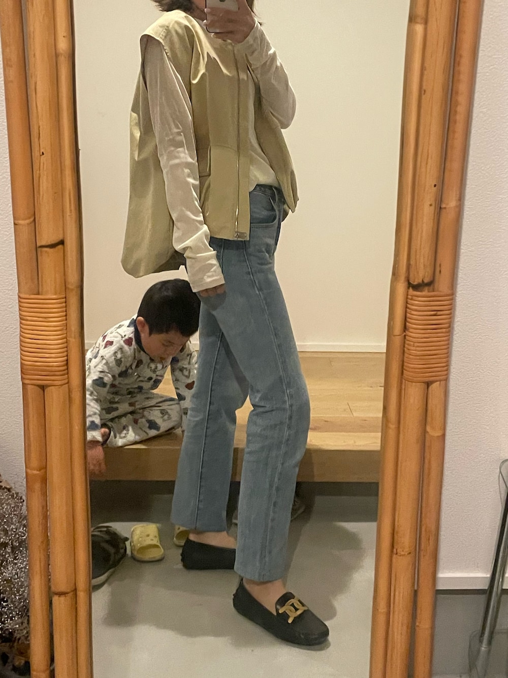 ブルー系のデニムパンツ、ブラック系のシューズ、イエロー系のベストを着用したレディースの春コーディネートの2枚目の写真