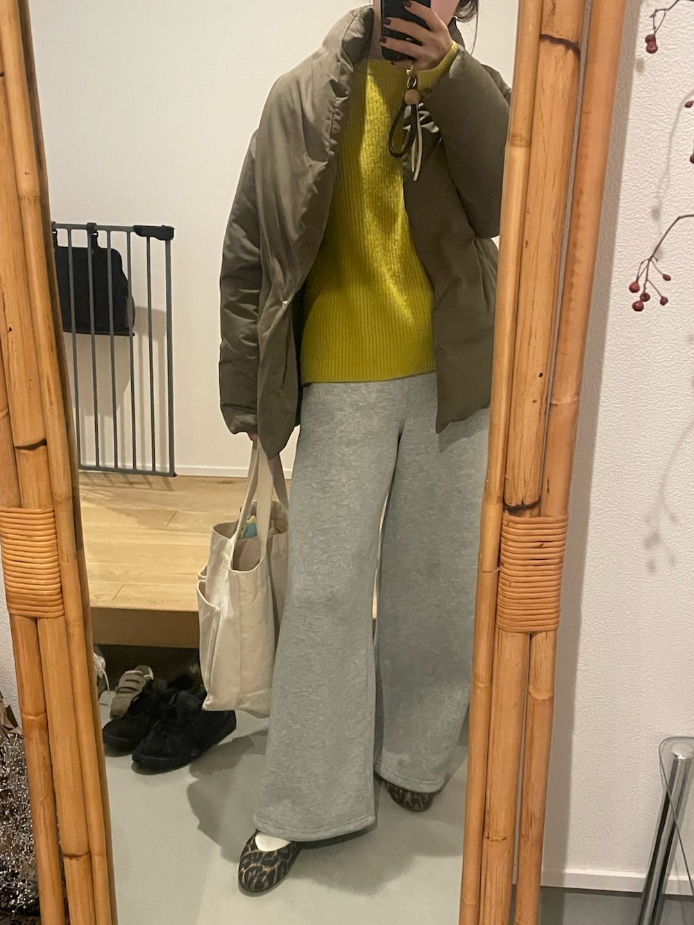 イエロー系のニット/セーター、グレー系のスウェットパンツを着用したレディースの冬コーディネートの2枚目の写真