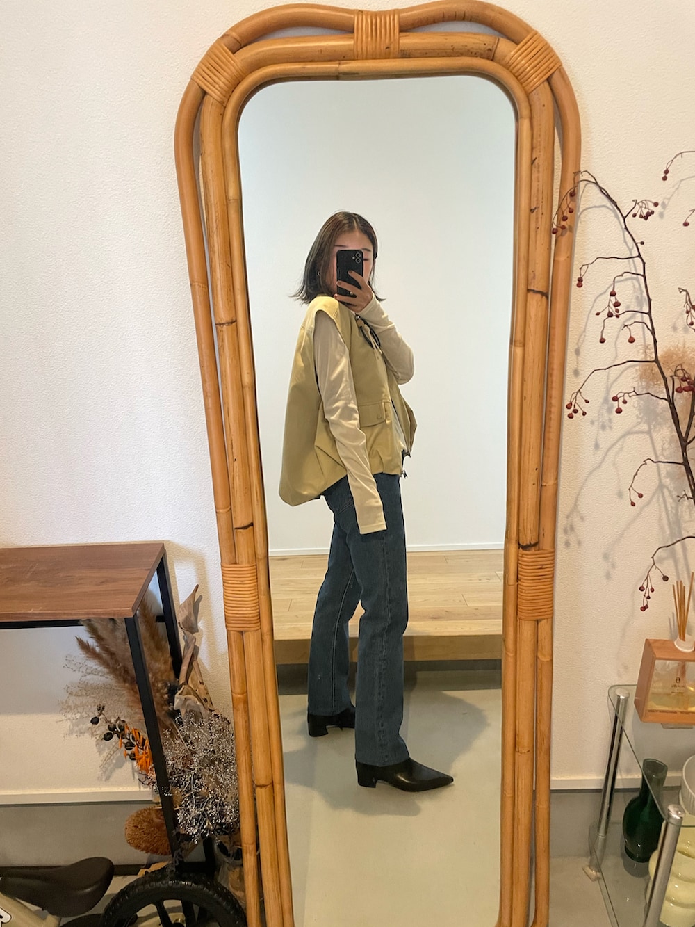 ブルー系のデニムパンツ、ブラック系のブーツ、イエロー系のベストを着用したレディースの秋コーディネートの2枚目の写真