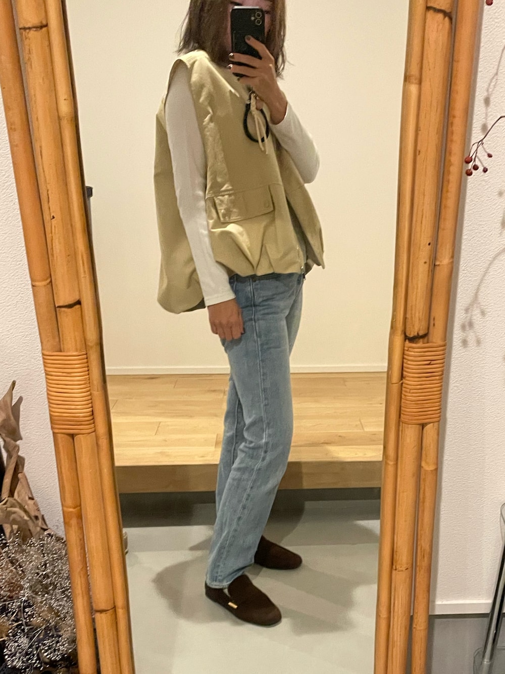 ブルー系のデニムパンツ、イエロー系のベスト、ブラウン系のローファーを着用したレディースの秋コーディネートの2枚目の写真