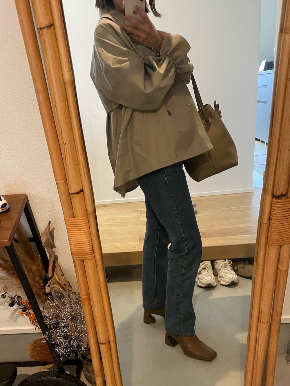 ブルー系のデニムパンツ、ベージュ系のバッグ、ブラウン系のブーツを着用したレディースの春コーディネートの4枚目の写真