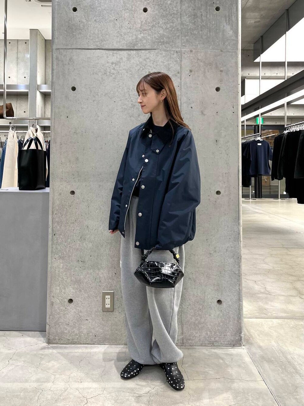 ブルー系のスウェット、ブラック系のショルダーバッグ、ブルー系のナイロンジャケットを着用したレディースの冬コーディネートの3枚目の写真