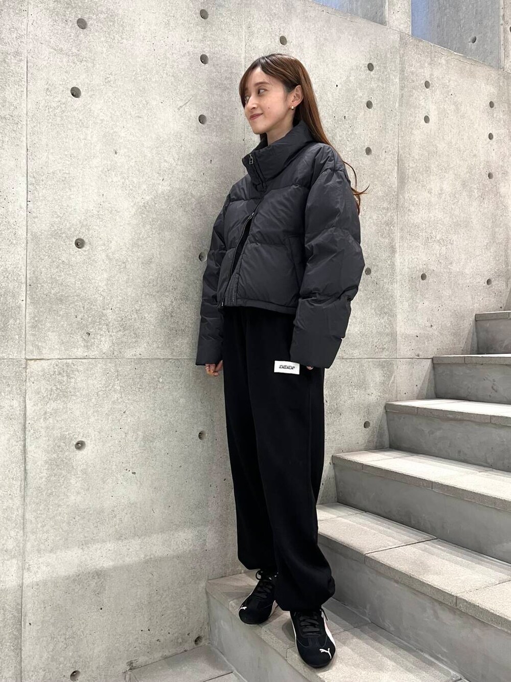 ホワイト系のTシャツ/カットソー、ブラック系のダウンジャケット/コート、ブラック系のスニーカーを着用したレディースの冬コーディネートの3枚目の写真