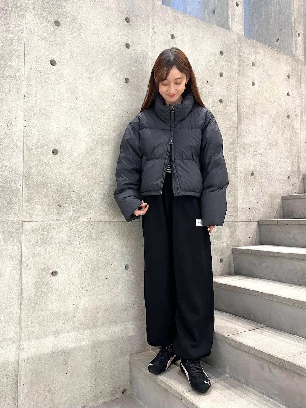 ホワイト系のTシャツ/カットソー、ブラック系のダウンジャケット/コート、ブラック系のスニーカーを着用したレディースの冬コーディネートの2枚目の写真