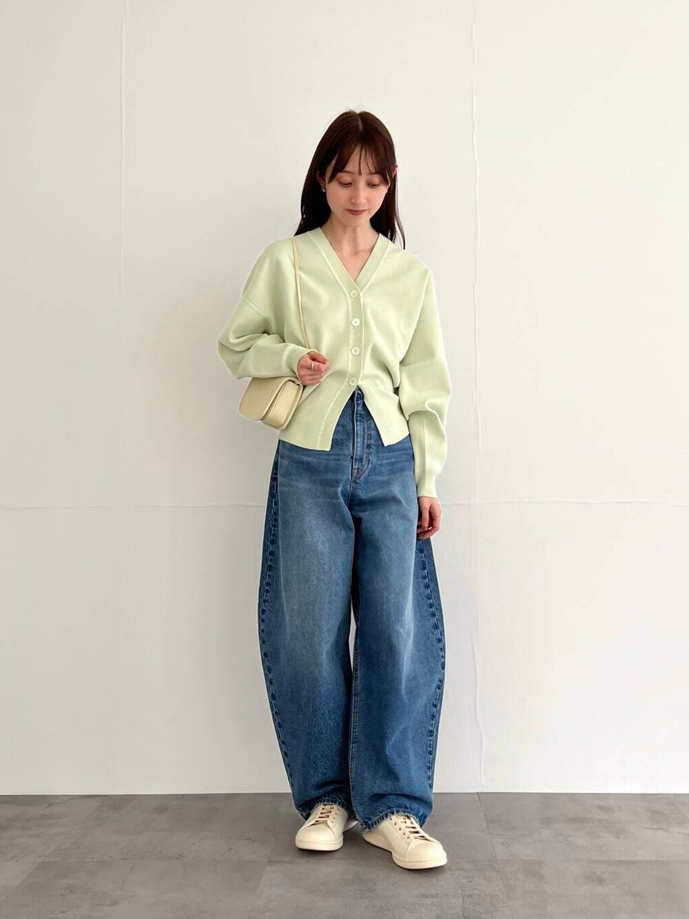 ブルー系のデニムパンツ、ホワイト系のショルダーバッグ、ホワイト系のスニーカーを着用したレディースの冬コーディネートの2枚目の写真