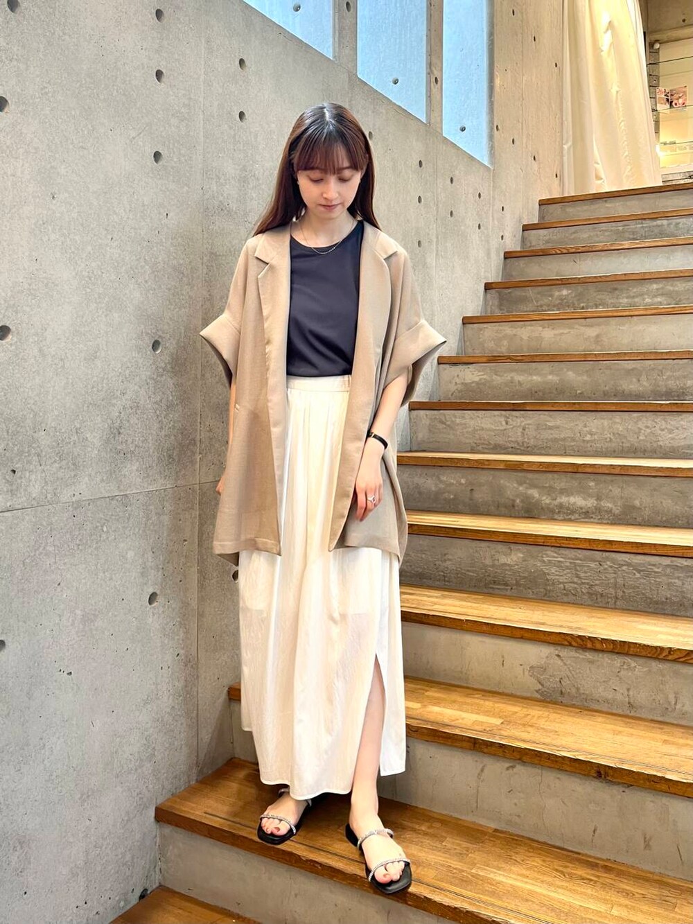 グレー系のTシャツ/カットソー、ブラック系のサンダル、ホワイト系のスカートを着用したレディースの夏コーディネートの2枚目の写真