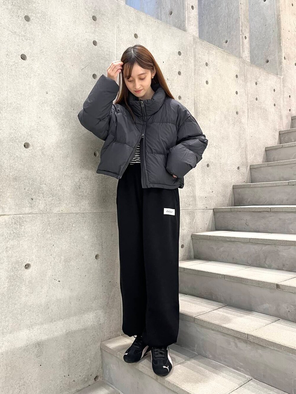 ホワイト系のTシャツ/カットソー、ブラック系のダウンジャケット/コート、ブラック系のスニーカーを着用したレディースの冬コーディネートの6枚目の写真