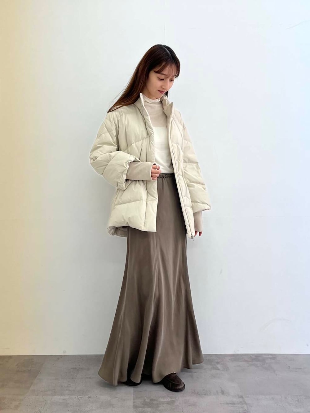 ホワイト系のダウンジャケット/コート、グリーン系のスカート、ホワイト系のTシャツ/カットソーを着用したレディースの冬コーディネートの3枚目の写真