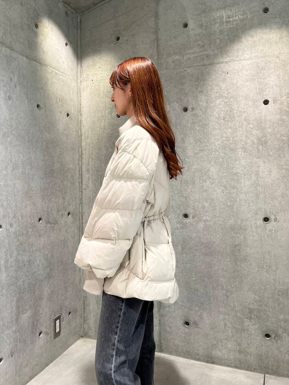 ブラック系のデニムパンツ、ブラック系のスニーカー、ホワイト系のダウンジャケット/コートを着用したレディースの秋コーディネートの8枚目の写真