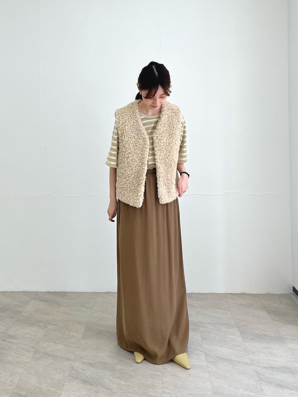 ホワイト系のベスト、ベージュ系のスカート、ベージュ系のパンプスを着用したレディースの夏コーディネートの3枚目の写真