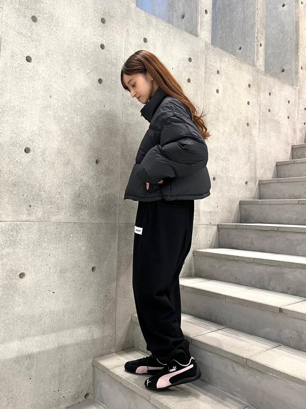 ホワイト系のTシャツ/カットソー、ブラック系のダウンジャケット/コート、ブラック系のスニーカーを着用したレディースの冬コーディネートの5枚目の写真