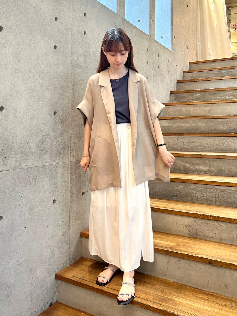 グレー系のTシャツ/カットソー、ブラック系のサンダル、ホワイト系のスカートを着用したレディースの夏コーディネートの7枚目の写真