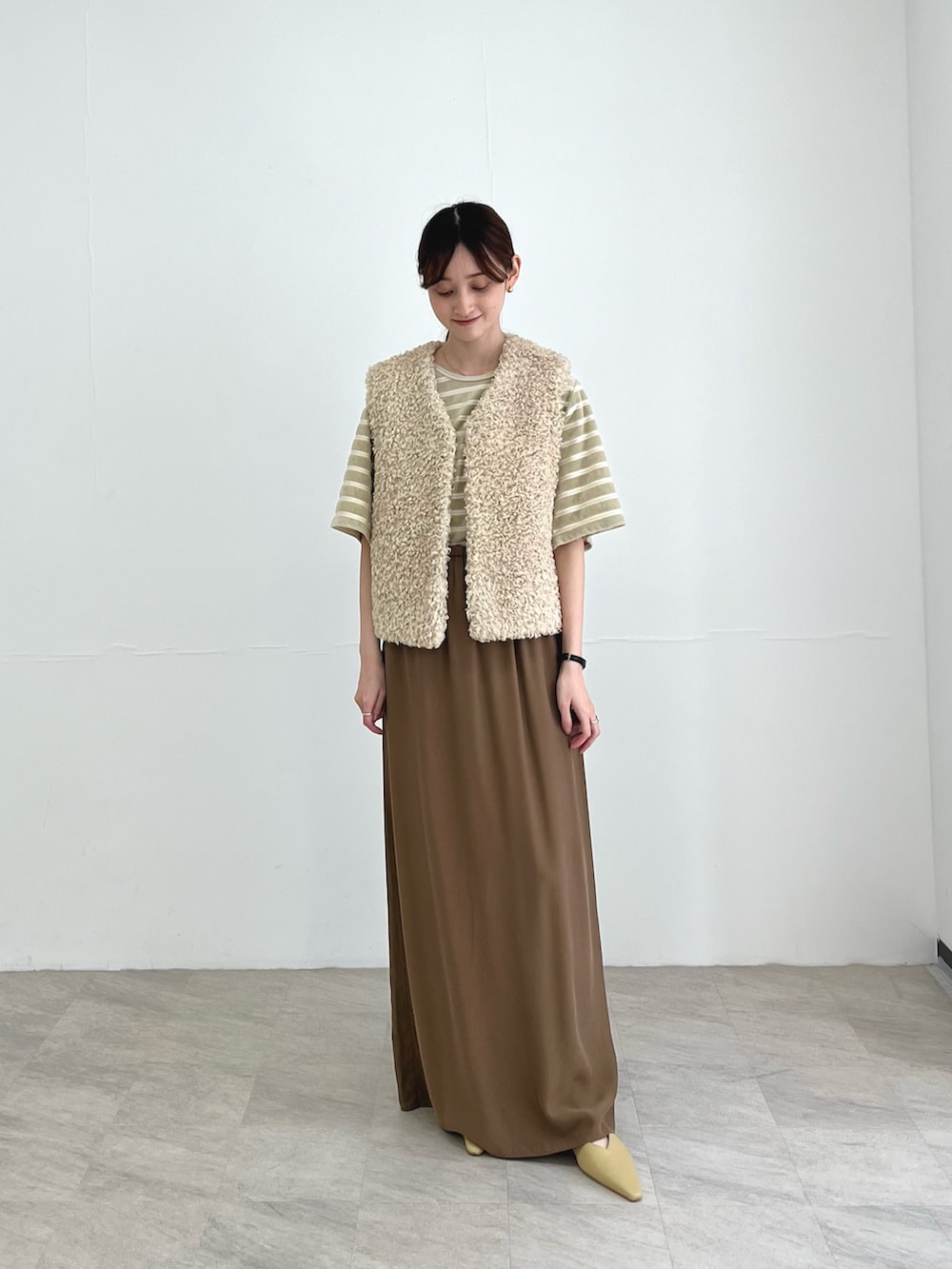 ホワイト系のベスト、ベージュ系のスカート、ベージュ系のパンプスを着用したレディースの夏コーディネートの2枚目の写真