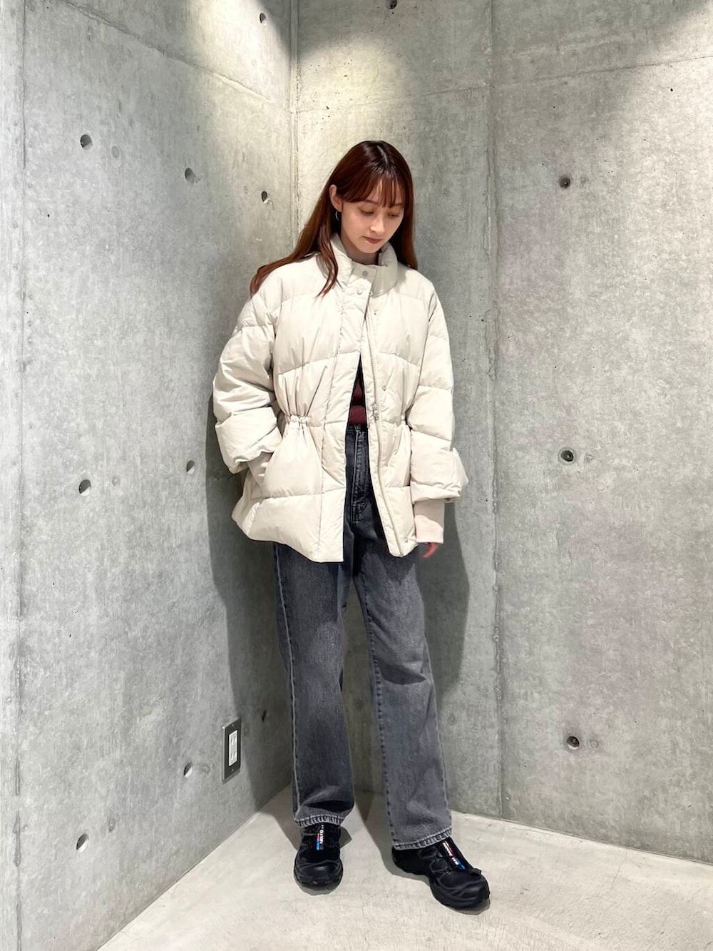 ブラック系のデニムパンツ、ブラック系のスニーカー、ホワイト系のダウンジャケット/コートを着用したレディースの秋コーディネートの4枚目の写真