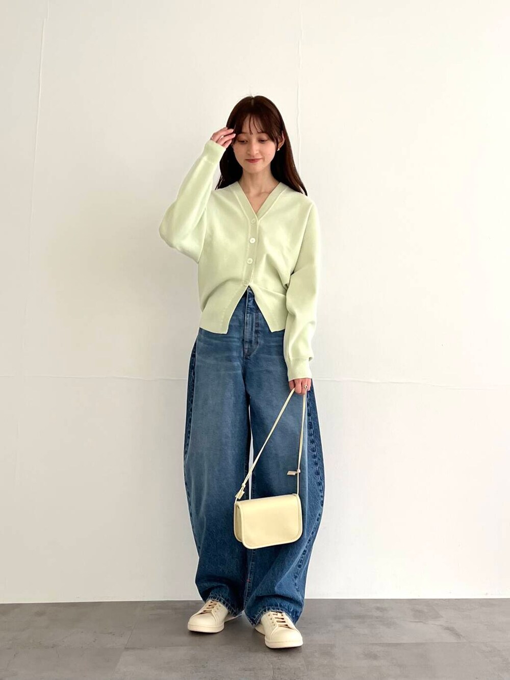 ブルー系のデニムパンツ、ホワイト系のショルダーバッグ、ホワイト系のスニーカーを着用したレディースの冬コーディネートの5枚目の写真