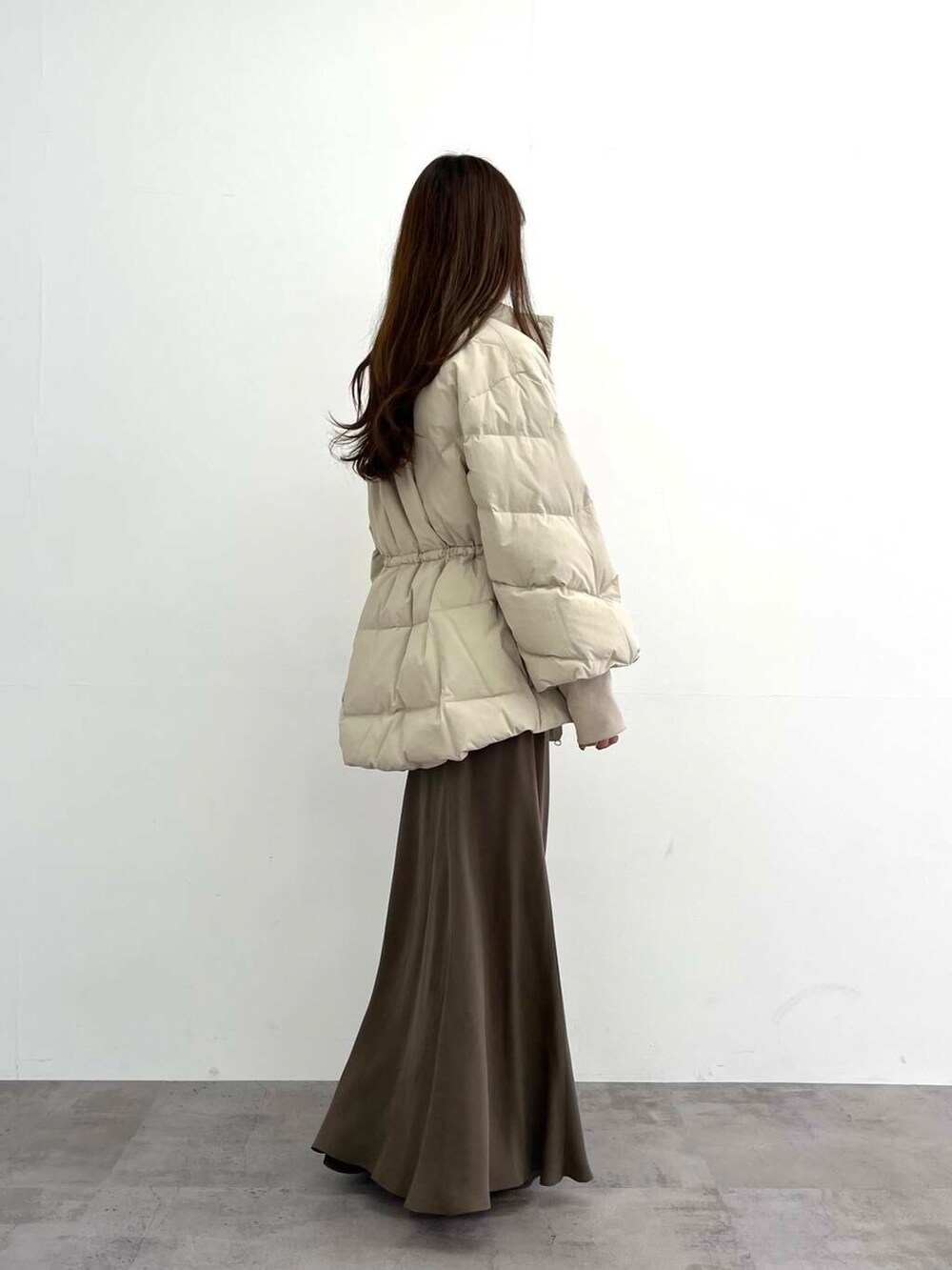 ホワイト系のダウンジャケット/コート、グリーン系のスカート、ホワイト系のTシャツ/カットソーを着用したレディースの冬コーディネートの4枚目の写真