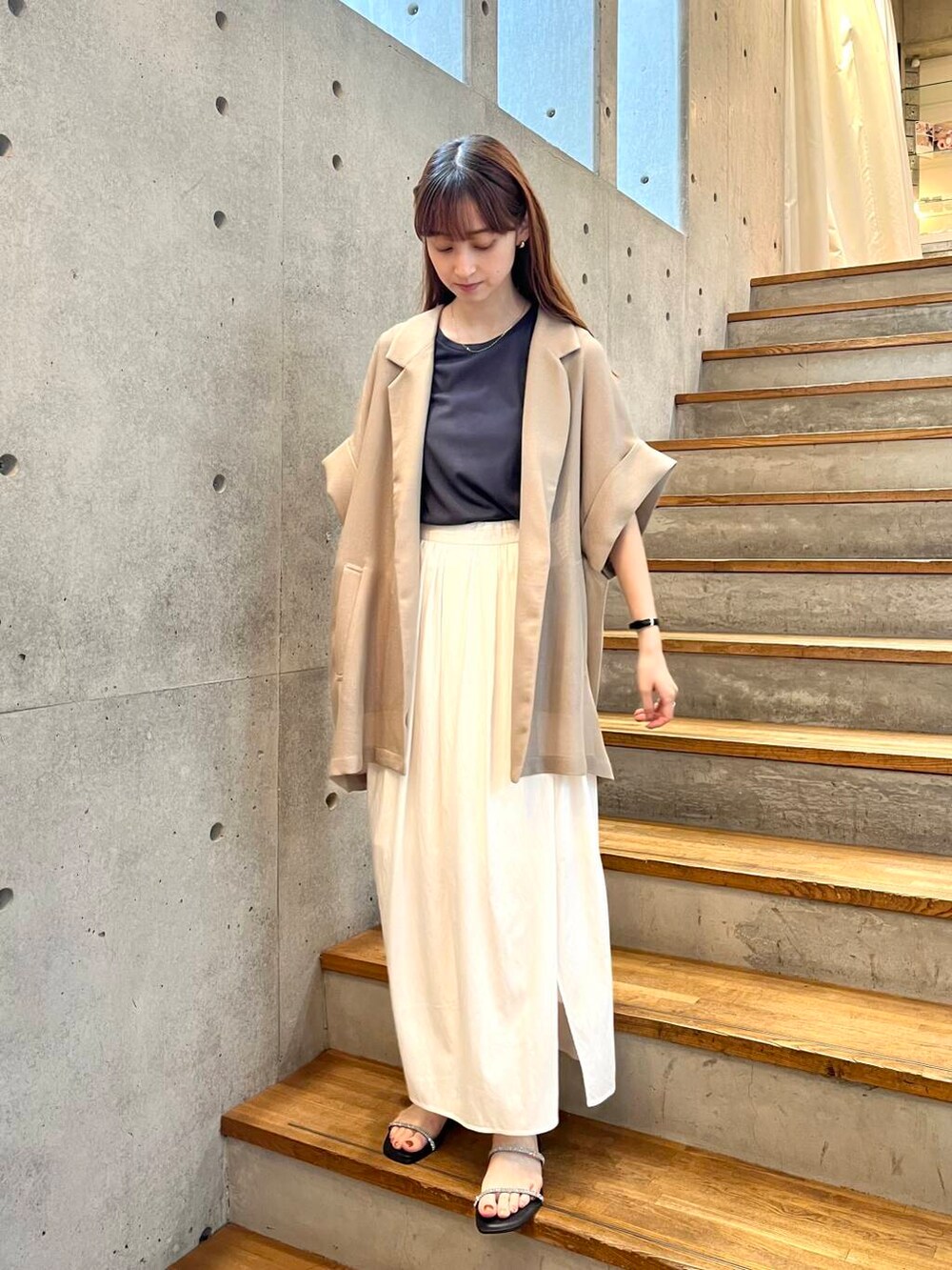 グレー系のTシャツ/カットソー、ブラック系のサンダル、ホワイト系のスカートを着用したレディースの夏コーディネートの6枚目の写真