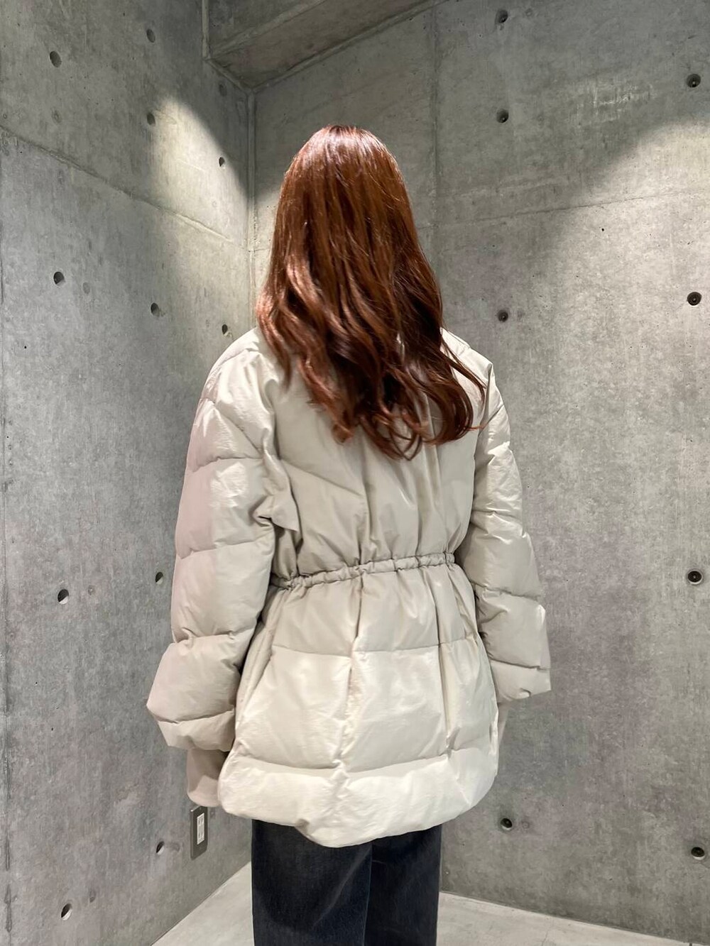 ブラック系のデニムパンツ、ブラック系のスニーカー、ホワイト系のダウンジャケット/コートを着用したレディースの秋コーディネートの9枚目の写真