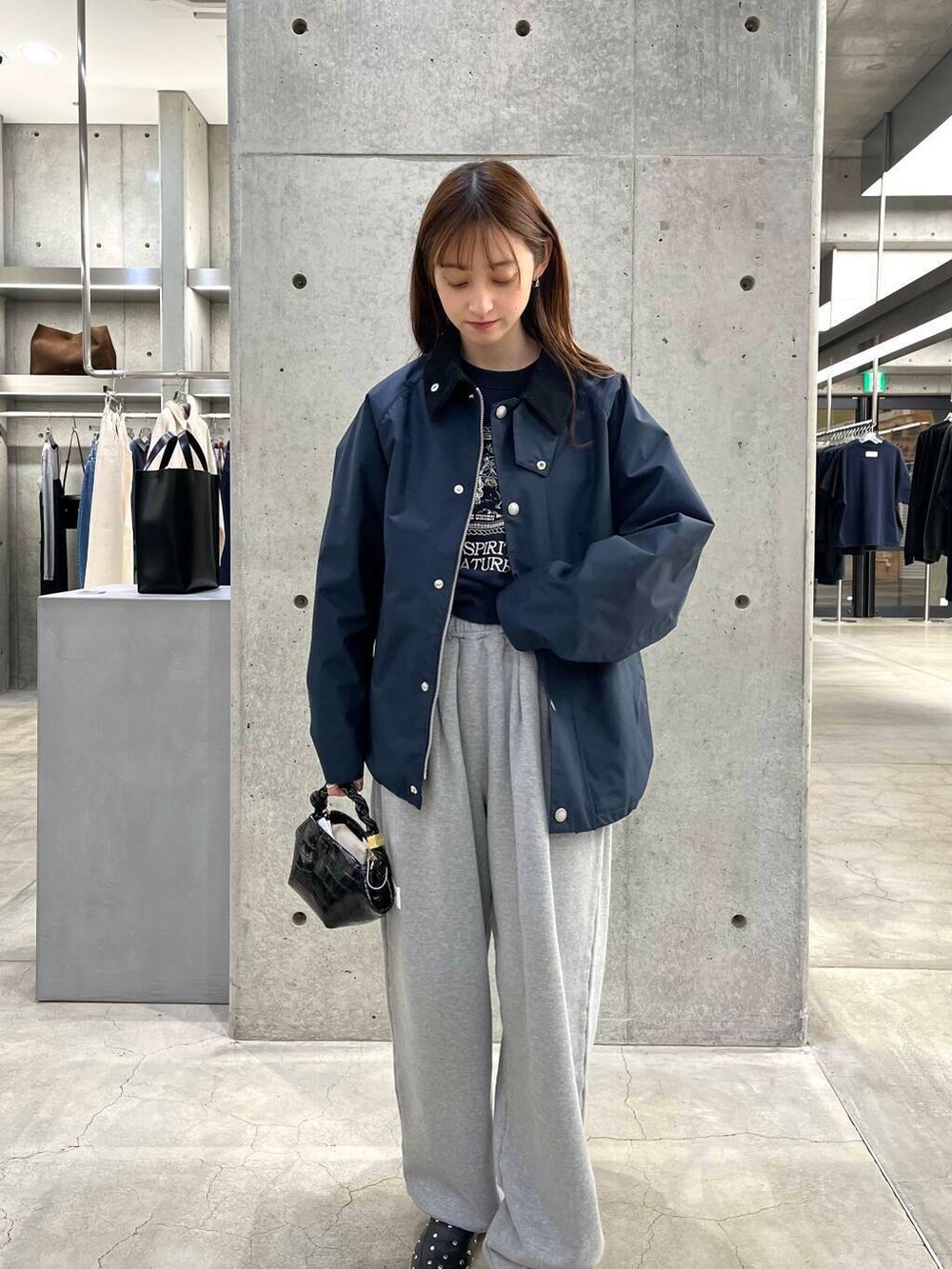 ブルー系のスウェット、ブラック系のショルダーバッグ、ブルー系のナイロンジャケットを着用したレディースの冬コーディネートの6枚目の写真