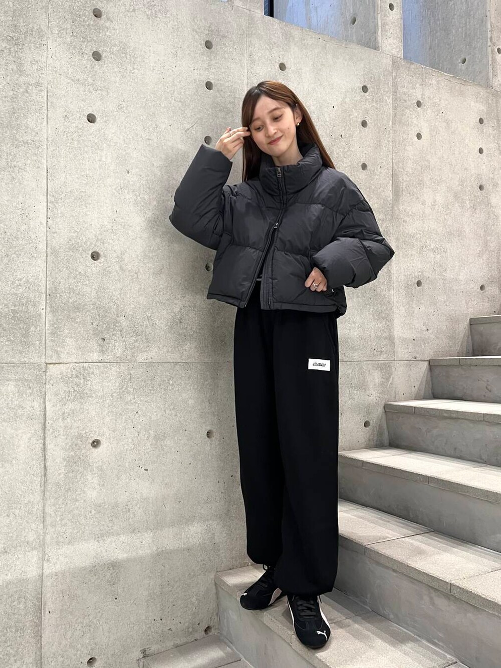 ホワイト系のTシャツ/カットソー、ブラック系のダウンジャケット/コート、ブラック系のスニーカーを着用したレディースの冬コーディネートの4枚目の写真