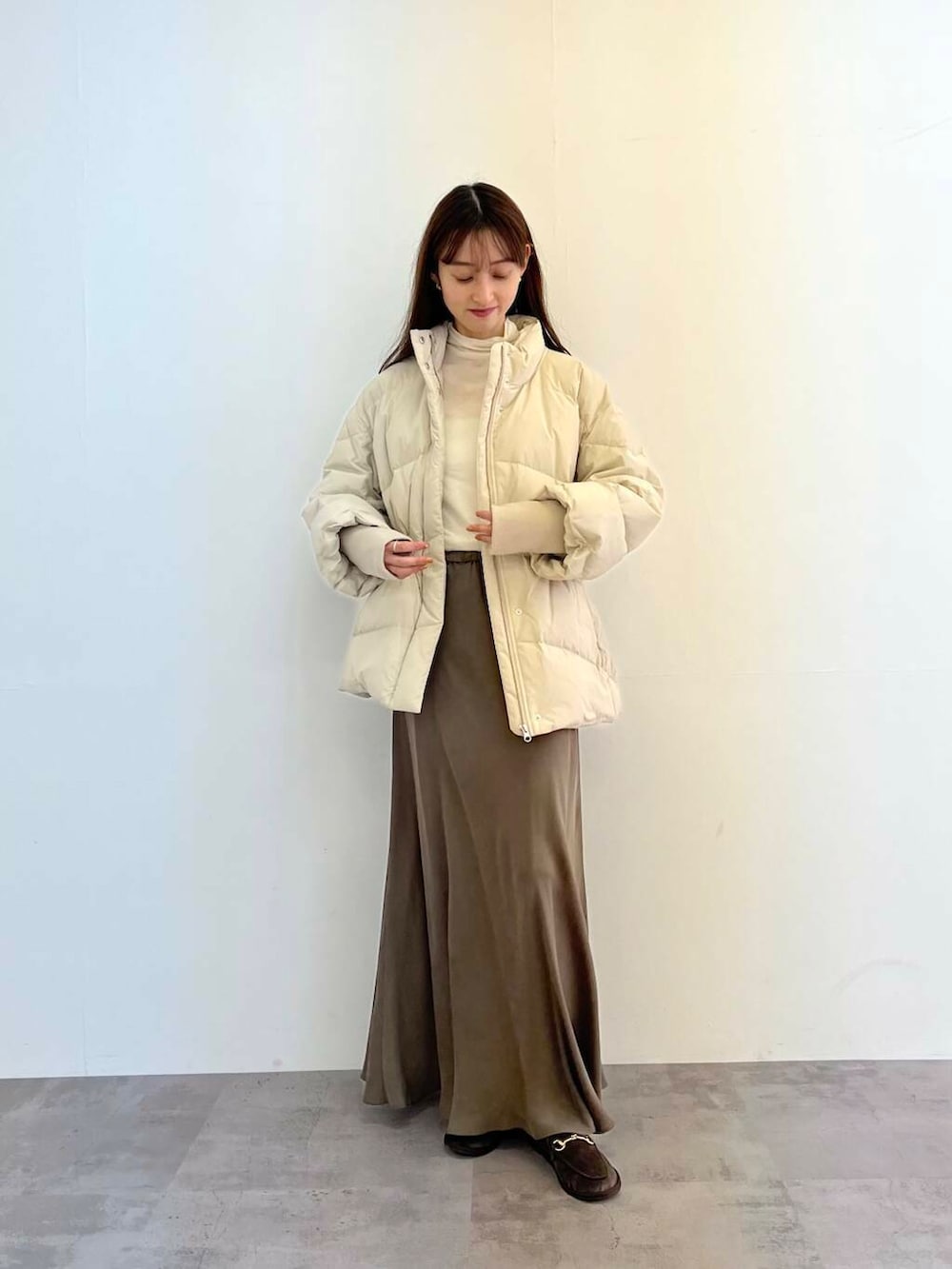 ホワイト系のダウンジャケット/コート、グリーン系のスカート、ホワイト系のTシャツ/カットソーを着用したレディースの冬コーディネートの2枚目の写真