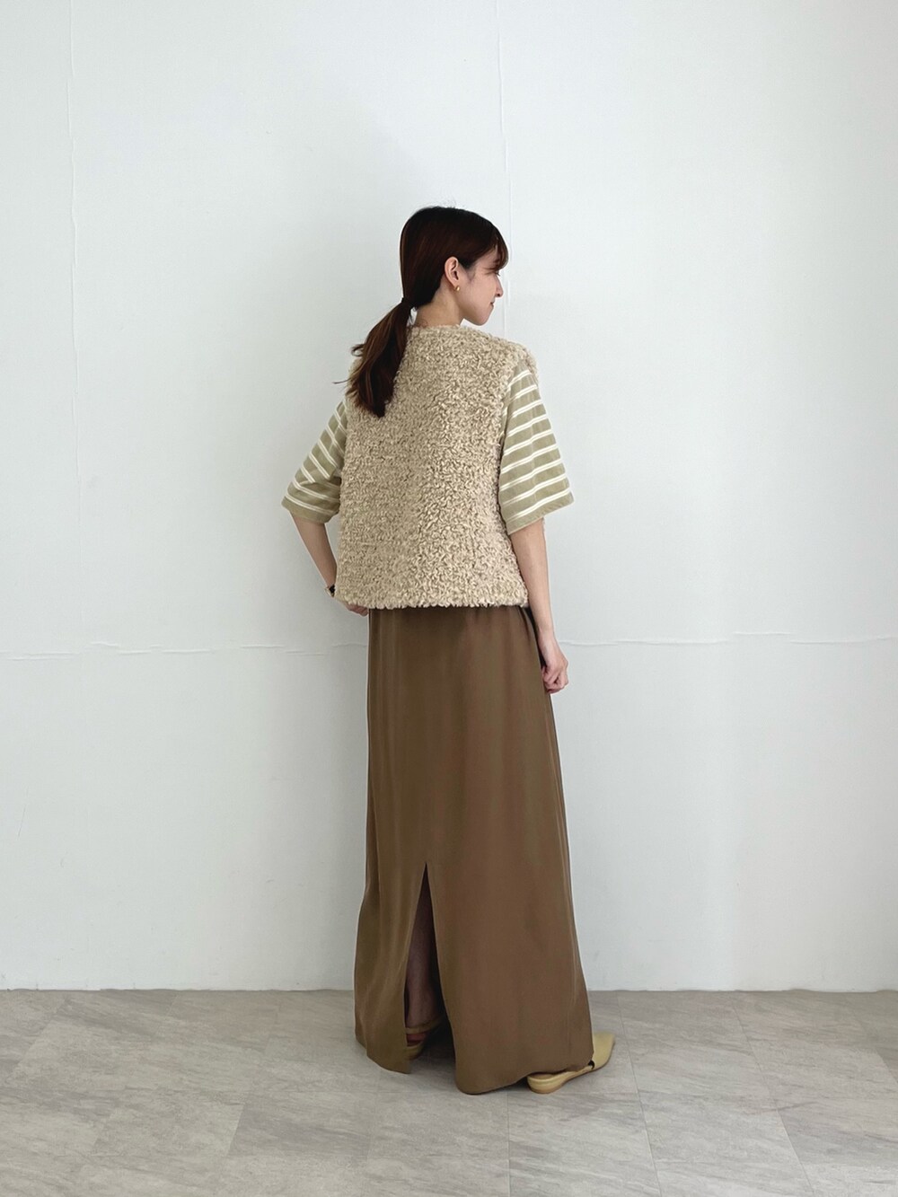 ホワイト系のベスト、ベージュ系のスカート、ベージュ系のパンプスを着用したレディースの夏コーディネートの4枚目の写真