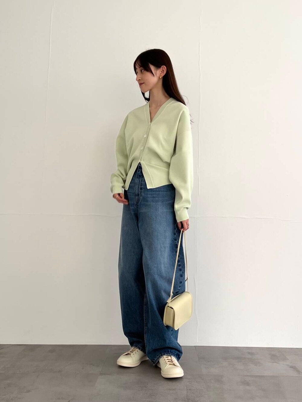 ブルー系のデニムパンツ、ホワイト系のショルダーバッグ、ホワイト系のスニーカーを着用したレディースの冬コーディネートの4枚目の写真