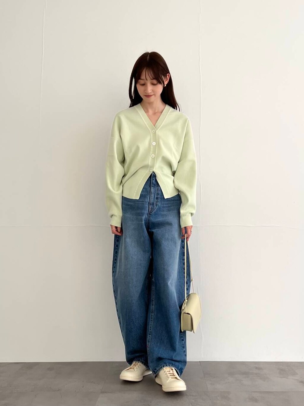 ブルー系のデニムパンツ、ホワイト系のショルダーバッグ、ホワイト系のスニーカーを着用したレディースの冬コーディネートの3枚目の写真