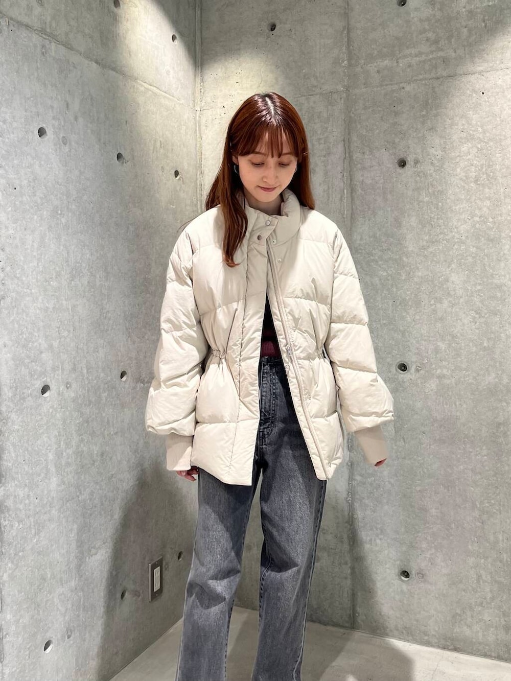 ブラック系のデニムパンツ、ブラック系のスニーカー、ホワイト系のダウンジャケット/コートを着用したレディースの秋コーディネートの7枚目の写真