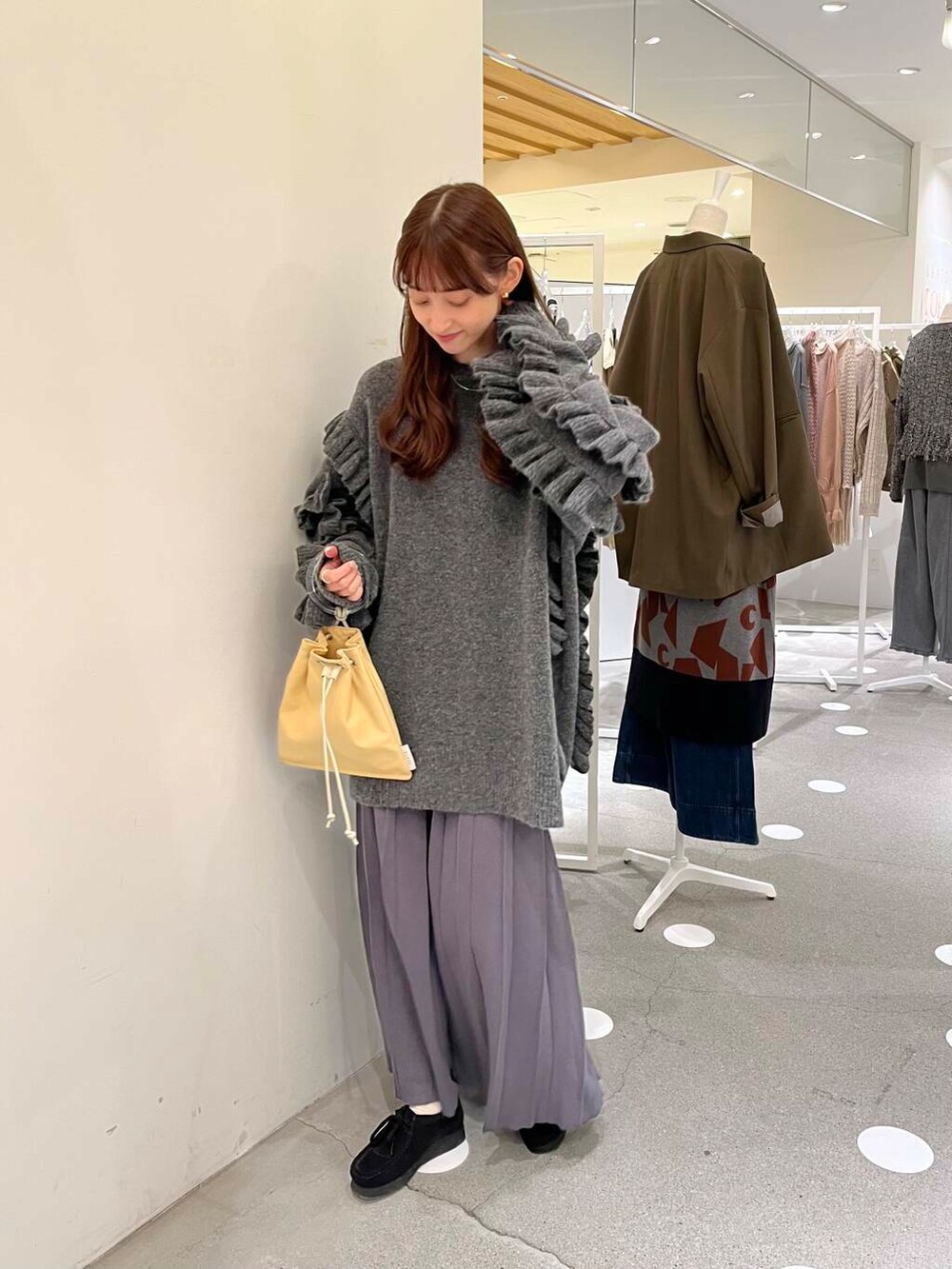 イエロー系のショルダーバッグ、グレー系のスカート、グレー系のニット/セーターを着用したレディースの秋コーディネートの3枚目の写真