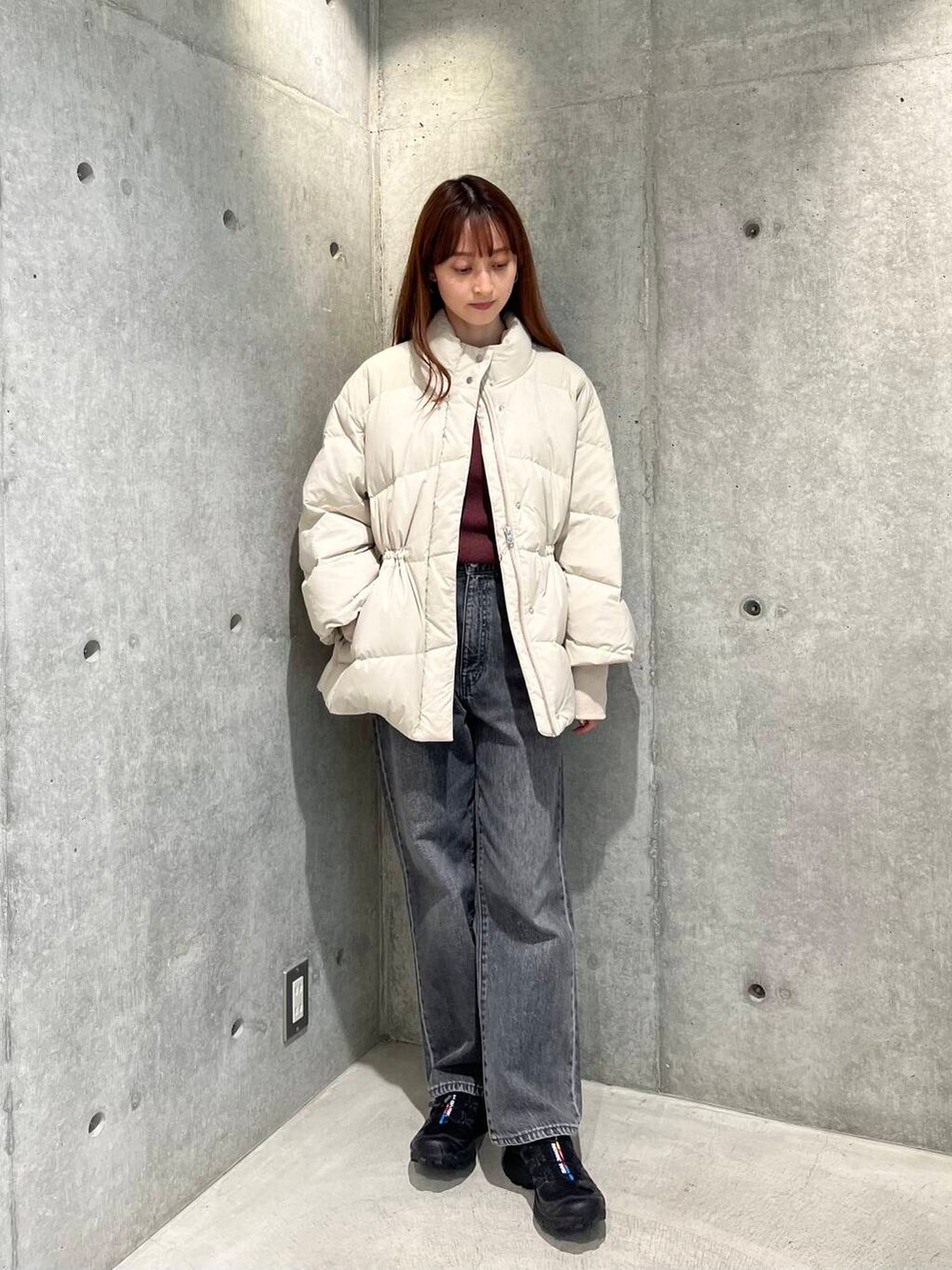 ブラック系のデニムパンツ、ブラック系のスニーカー、ホワイト系のダウンジャケット/コートを着用したレディースの秋コーディネートの3枚目の写真