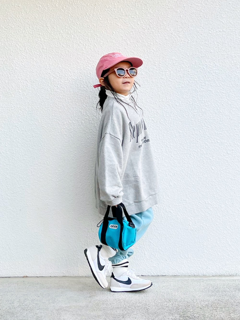 グレー系のトップス、ホワイト系のTシャツ/カットソー、ブルー系のショルダーバッグを着用したキッズの冬コーディネートの2枚目の写真