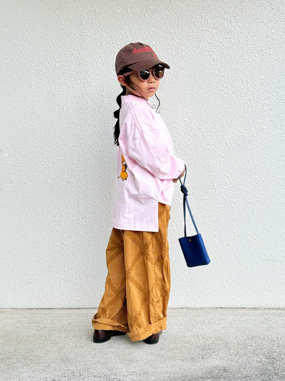 ピンク系のTシャツ/カットソー、ブルー系のショルダーバッグ、ベージュ系のパンツを着用したキッズの秋コーディネートの2枚目の写真