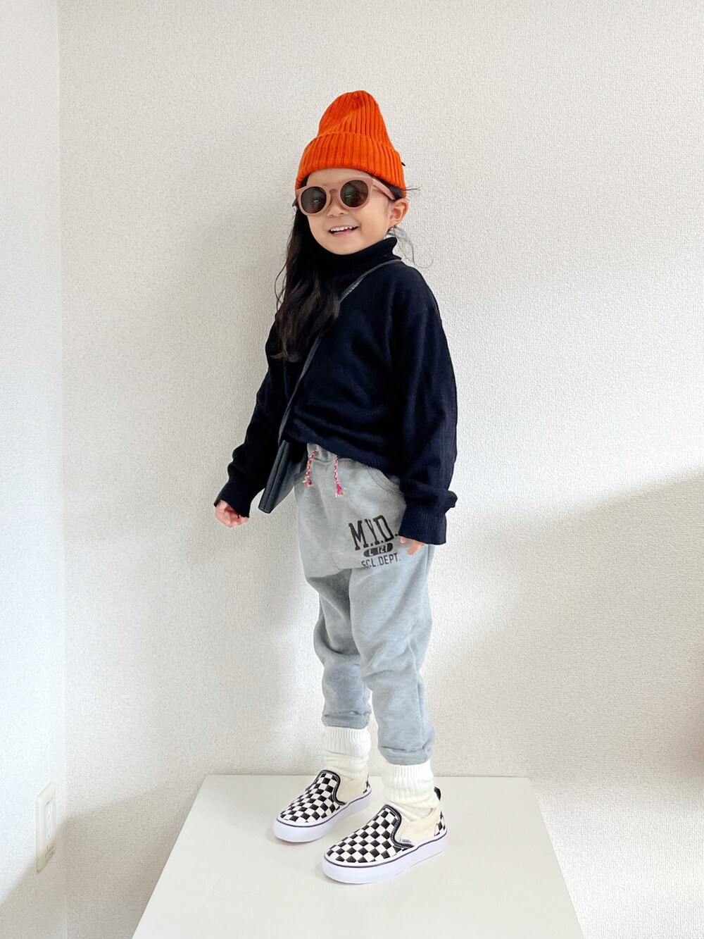 ブラック系のニット/セーター、ベージュ系のノーカラーコート、グレー系のスウェットパンツを着用したキッズの秋コーディネートの2枚目の写真