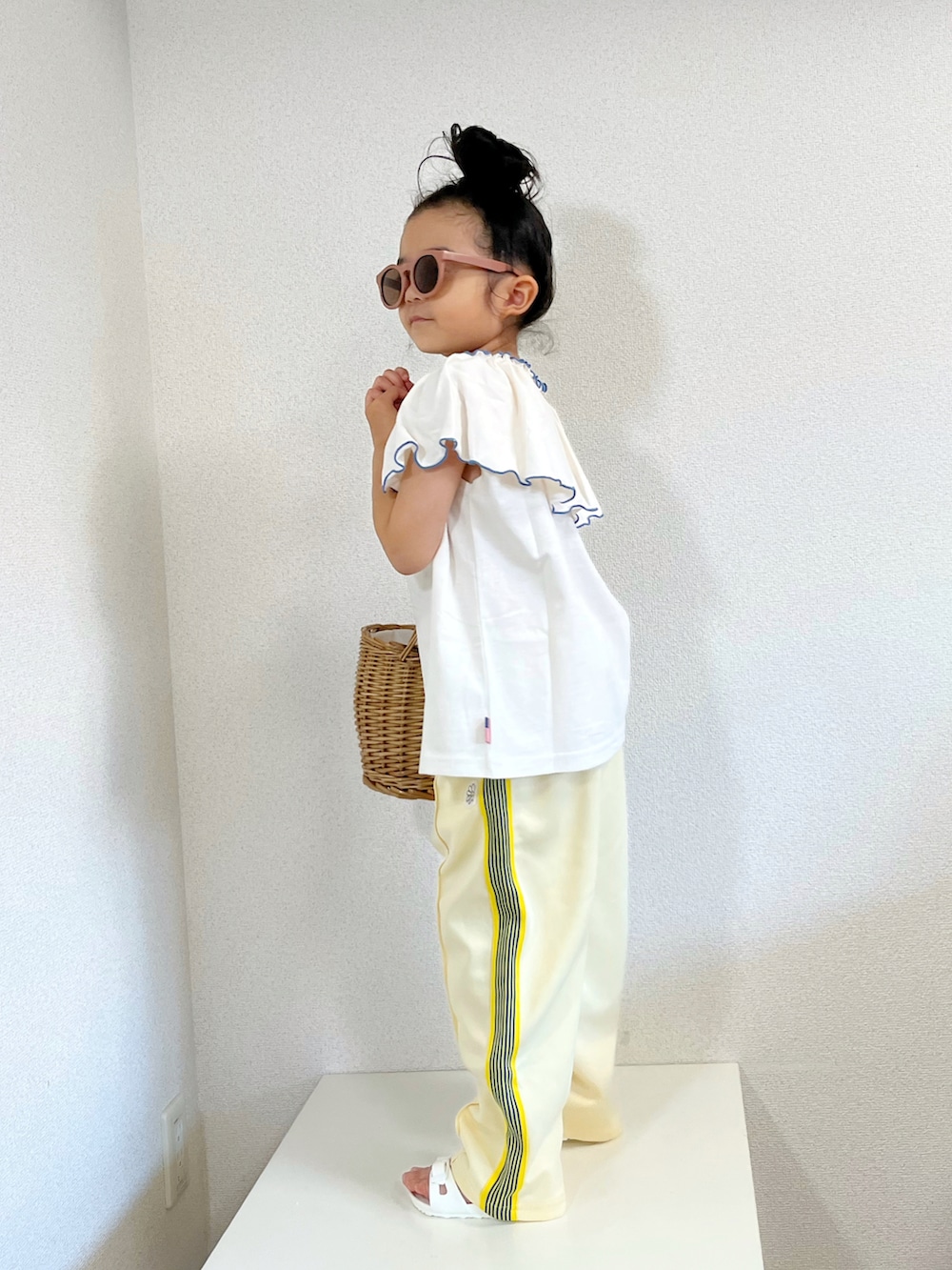 ホワイト系のTシャツ/カットソー、イエロー系のその他パンツ、ベージュ系のかごバッグを着用したキッズの夏コーディネートの3枚目の写真