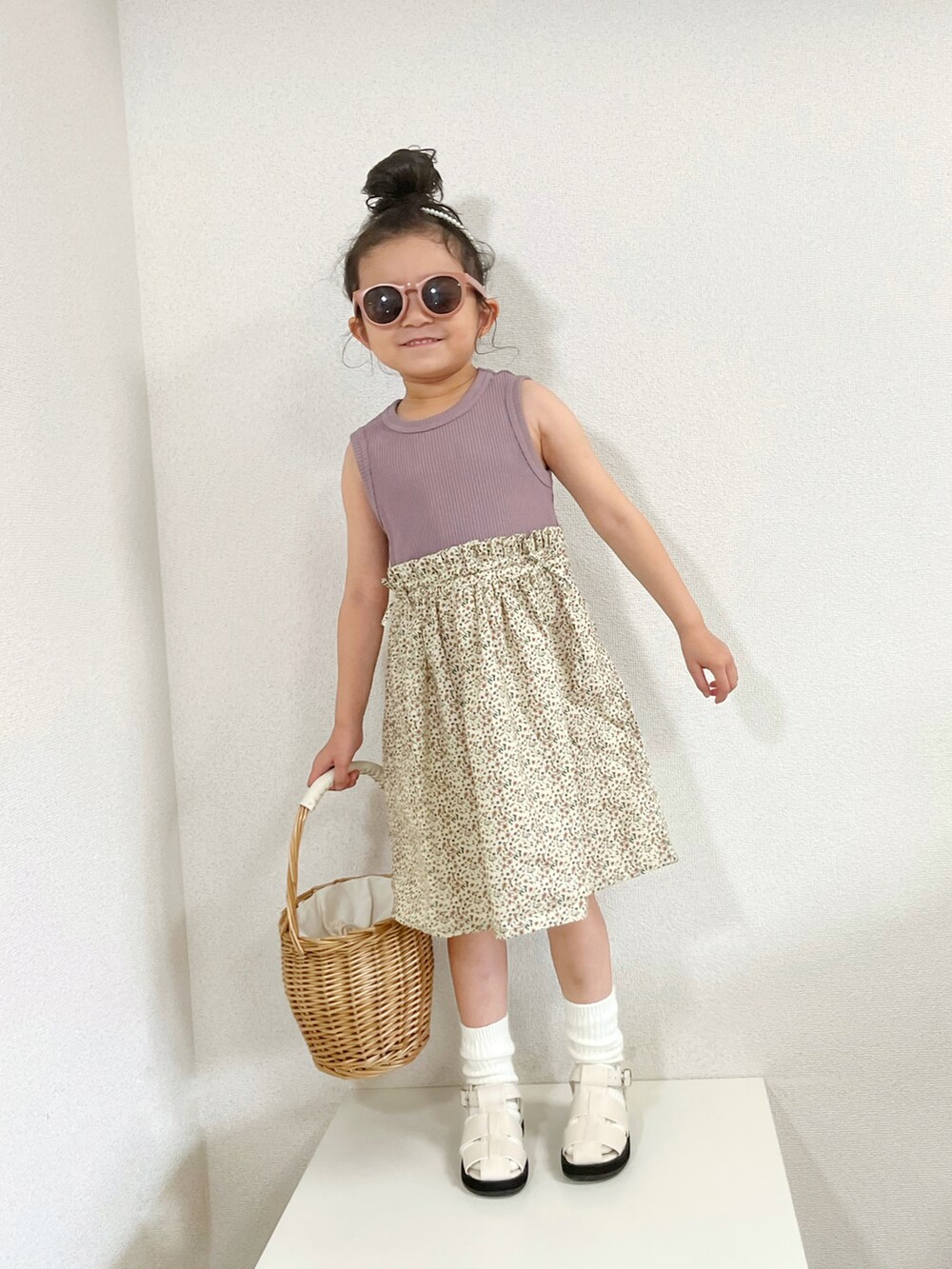 パープル系のワンピース、ベージュ系のかごバッグ、ホワイト系のサンダルを着用したキッズの夏コーディネートの3枚目の写真