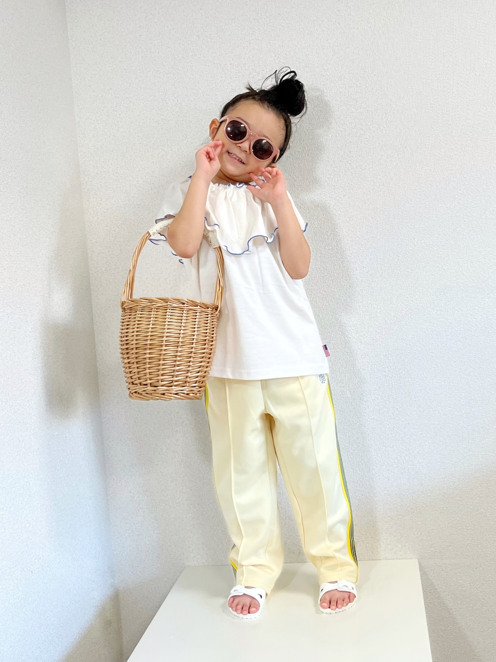 ホワイト系のTシャツ/カットソー、イエロー系のその他パンツ、ベージュ系のかごバッグを着用したキッズの夏コーディネートの2枚目の写真