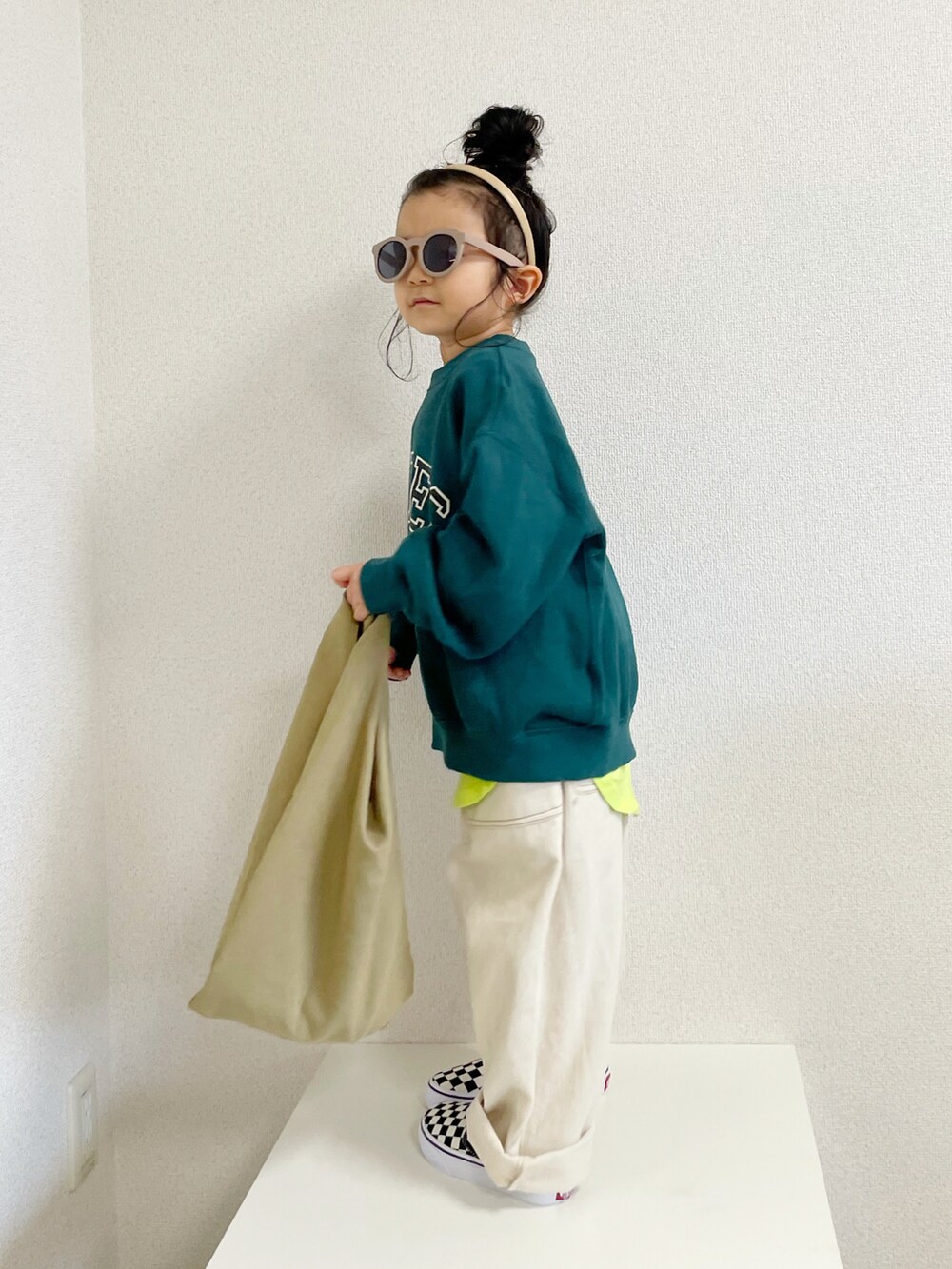 グリーン系のスウェット、イエロー系のタンクトップ、ベージュ系のエコバッグ/サブバッグを着用したキッズの春コーディネートの2枚目の写真