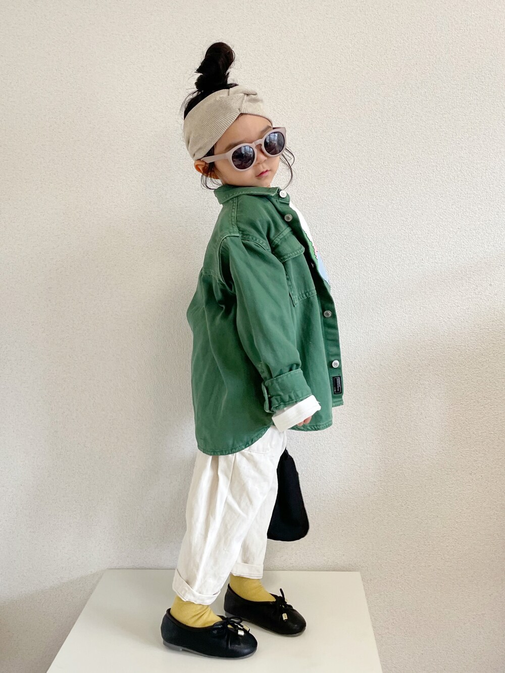 ホワイト系のトップス、グリーン系のデニムジャケット、ブラック系のトートバッグを着用したキッズの春コーディネートの3枚目の写真