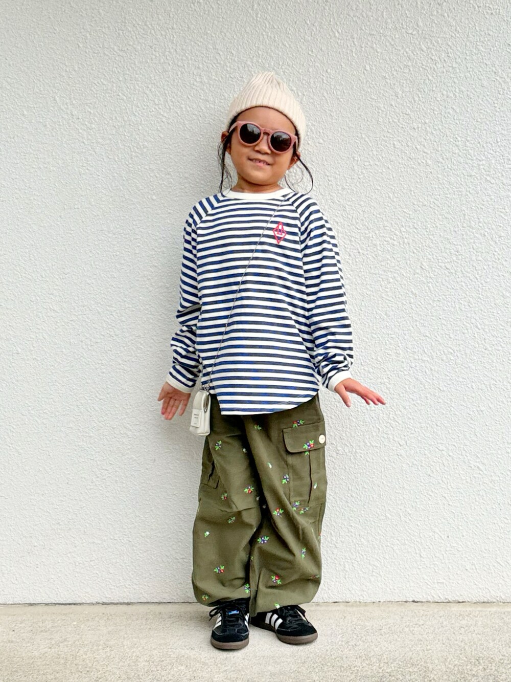 ホワイト系のトップス、グリーン系のカーゴパンツ、ブラック系のスニーカーを着用したキッズの秋コーディネートの2枚目の写真