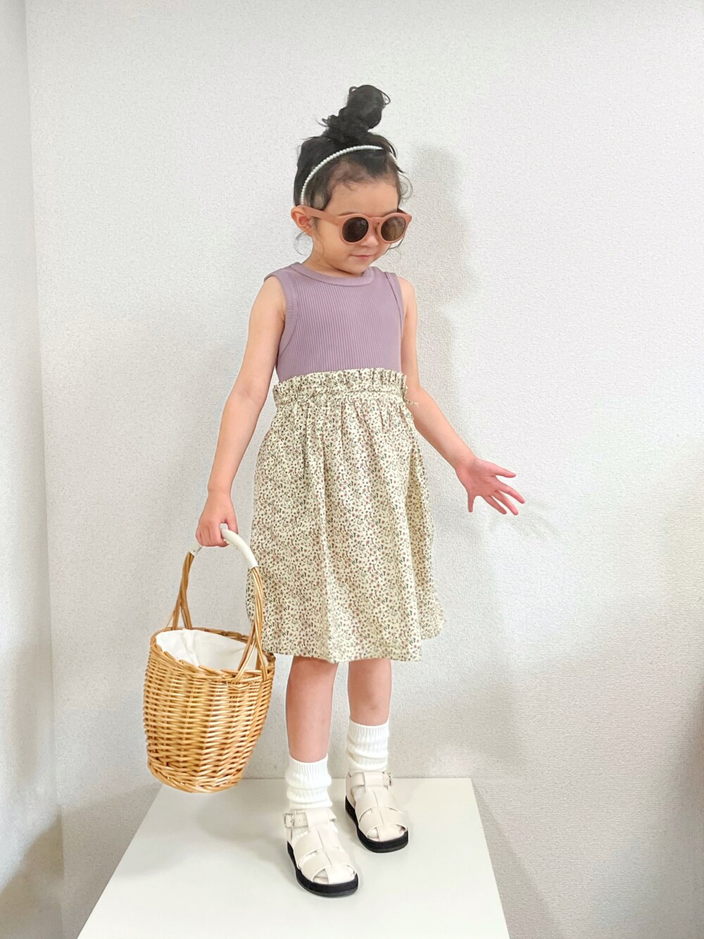 パープル系のワンピース、ベージュ系のかごバッグ、ホワイト系のサンダルを着用したキッズの夏コーディネートの2枚目の写真