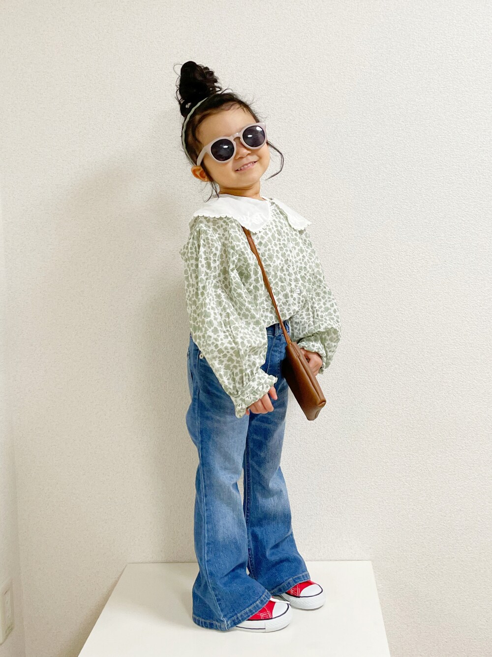 グリーン系のトップス、ブラウン系のショルダーバッグ、ブルー系のデニムパンツを着用したキッズの春コーディネートの2枚目の写真