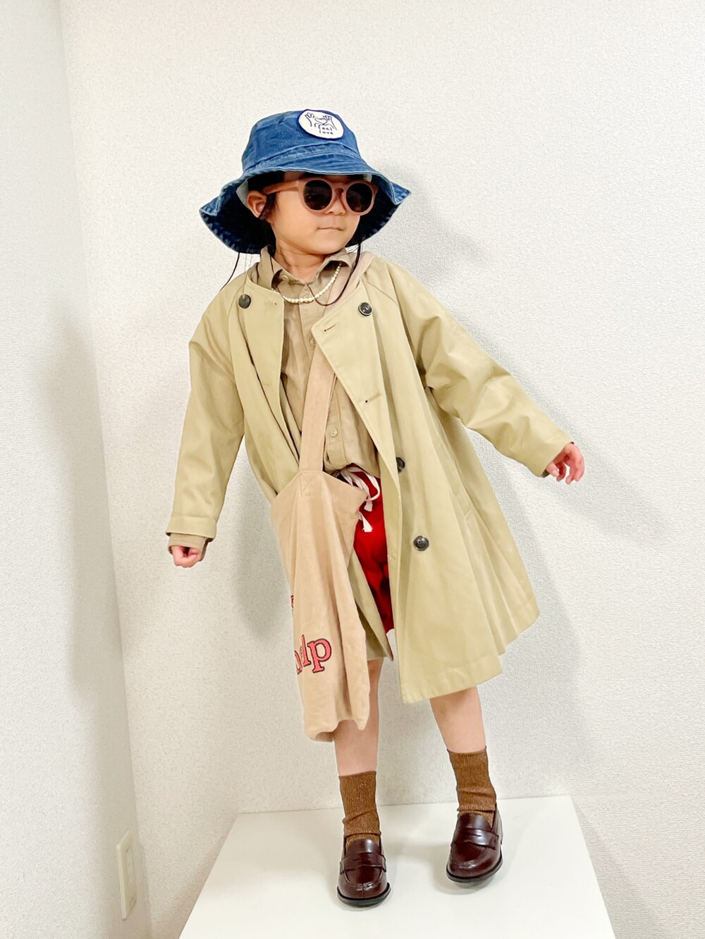 ベージュ系のトップス、ベージュ系のノーカラーコート、ベージュ系のトートバッグを着用したキッズの春コーディネートの3枚目の写真