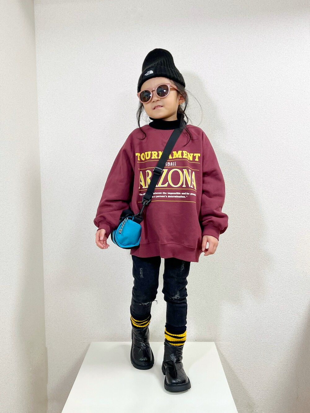 レッド系のスウェット、ブラック系のニット/セーター、ブルー系のショルダーバッグを着用したキッズの冬コーディネートの2枚目の写真