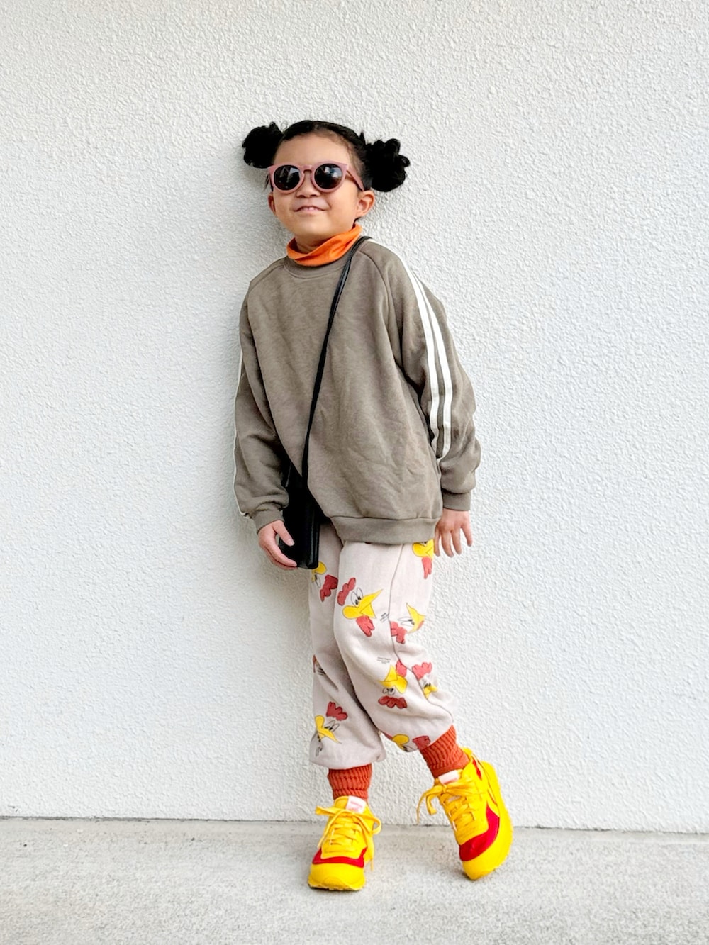 グリーン系のスウェット、オレンジ系のTシャツ/カットソー、ブラック系のショルダーバッグを着用したキッズの冬コーディネートの2枚目の写真