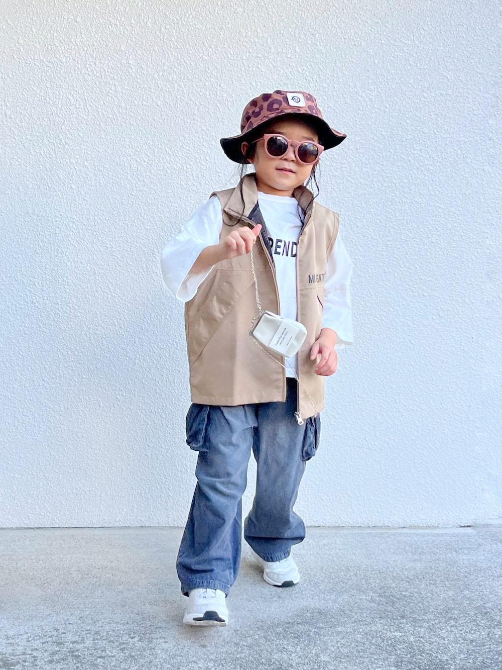 ホワイト系のTシャツ/カットソー、ベージュ系のベスト、ブラック系のデニムパンツを着用したキッズの秋コーディネートの2枚目の写真