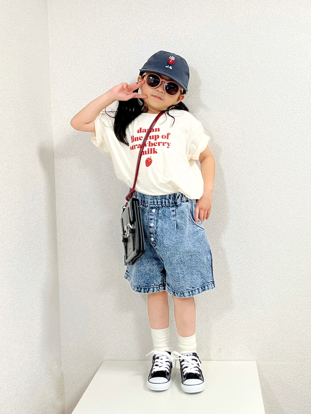 ベージュ系のTシャツ/カットソー、ブラック系のバッグ、ブルー系のデニムパンツを着用したキッズの夏コーディネートの2枚目の写真