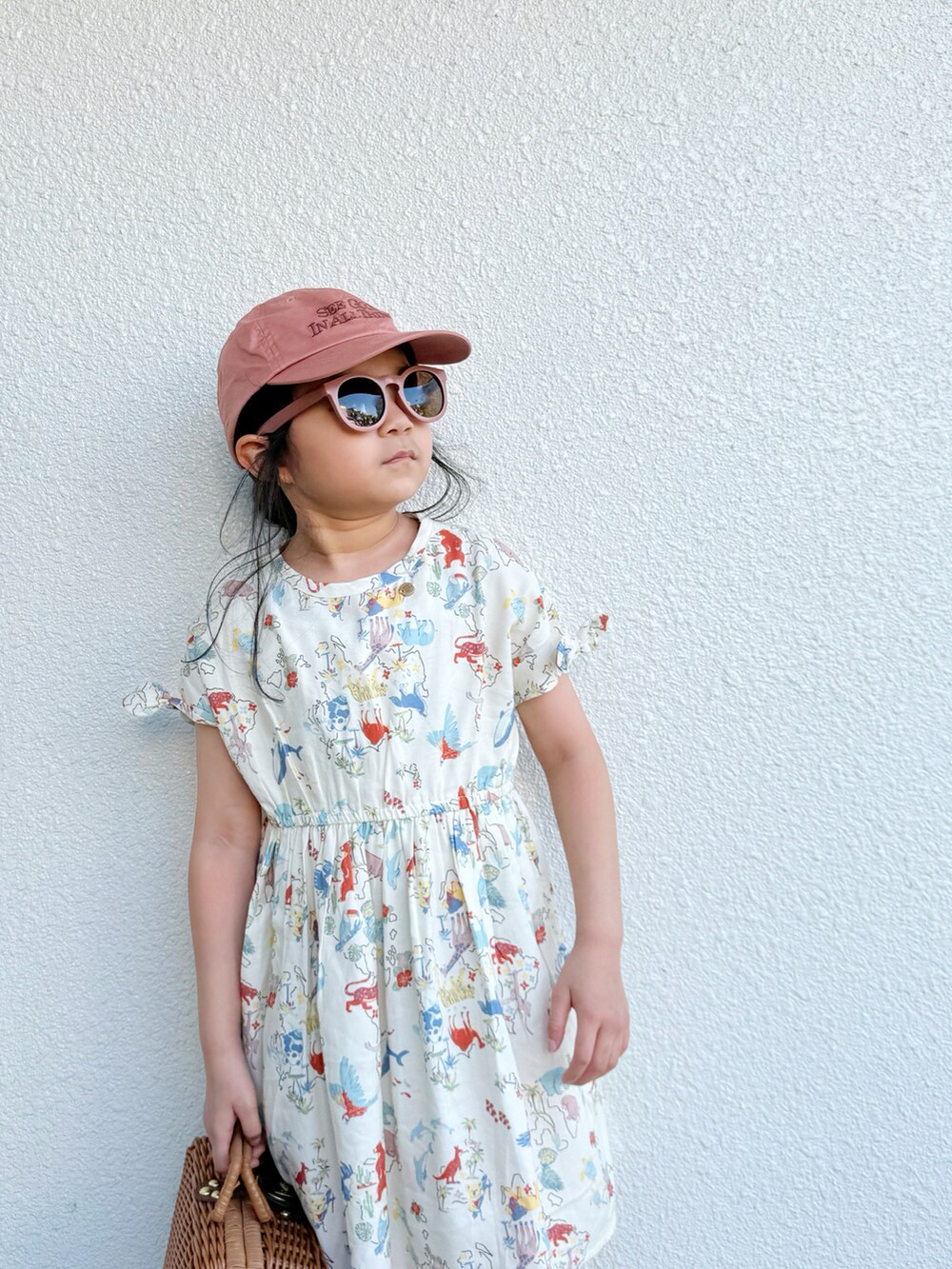 ベージュ系のワンピース、イエロー系のスニーカー、ゴールド系のハンドバッグを着用したキッズの夏コーディネートの2枚目の写真